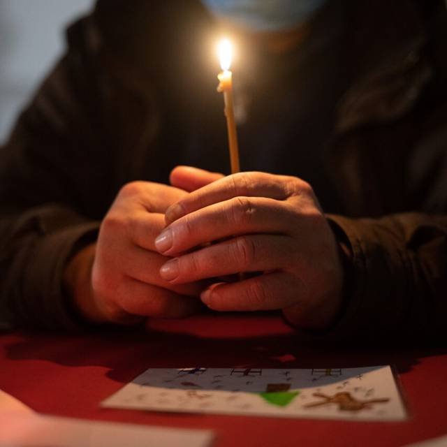 Besucher sitzt in der Weißfrauen Diakoniekirche mit einer Kerze beim Gottesdienst an einem Tisch. Die Kirche im Bahnhofsviertel öffnet bei der Veranstaltung am Heiligen Abend ihre Türen und schließt sie erst am ersten Weihnachtsfeiertag wieder. Das Angebot mit Gottesdienst, Weihnachtsessen, Musik und Übernachtungsmöglichkeit richtet sich an alle Menschen im Bahnhofsviertel. Hauptsächlich sind die Besucher jedoch wohnungslos oder haben sehr geringe finanzielle Mittel zur Verfügung.