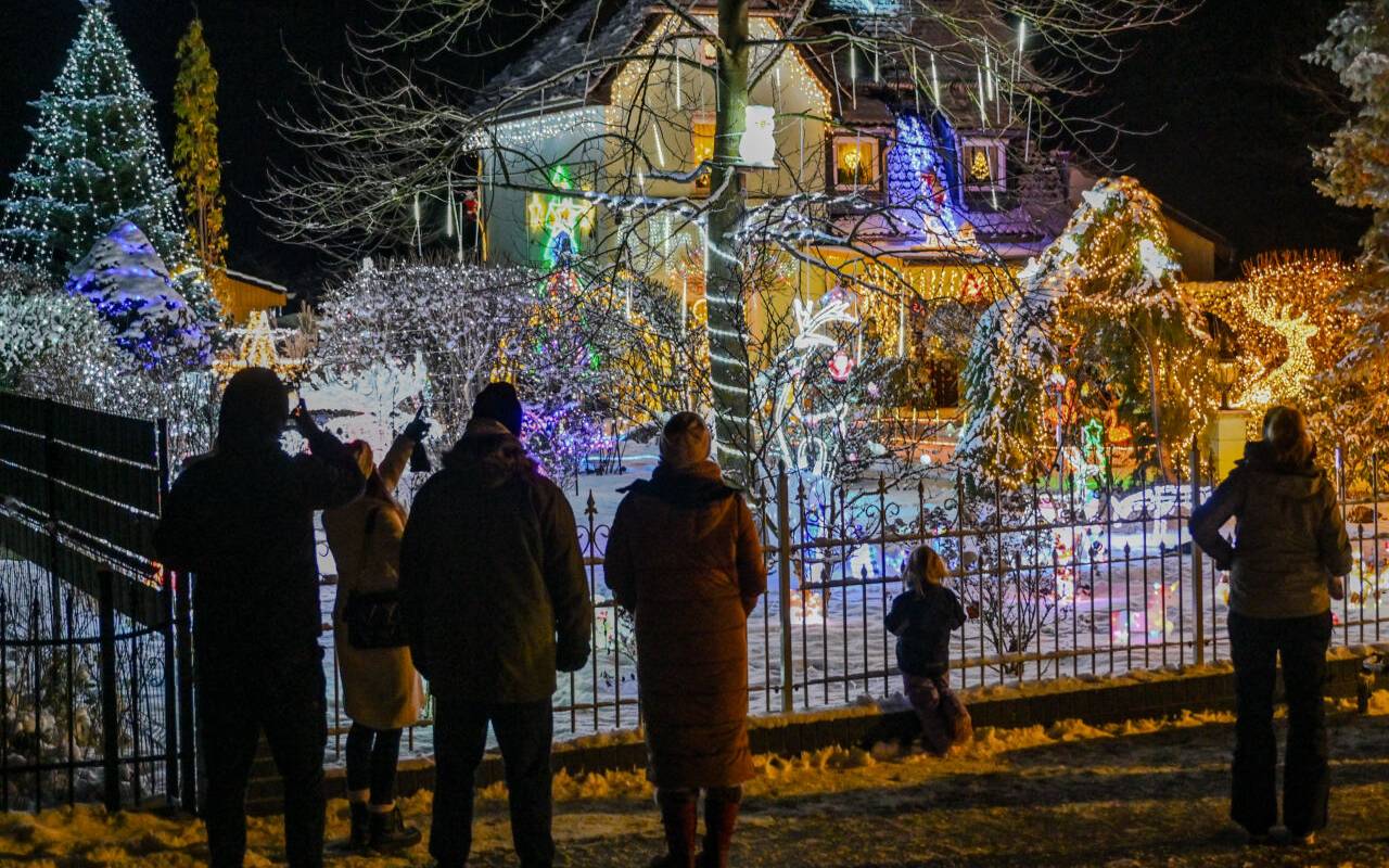 Schaulustige stehen vor dem weihnachtlich hell beleuchteten Garten der Familie Muschner in Ostbrandenburg