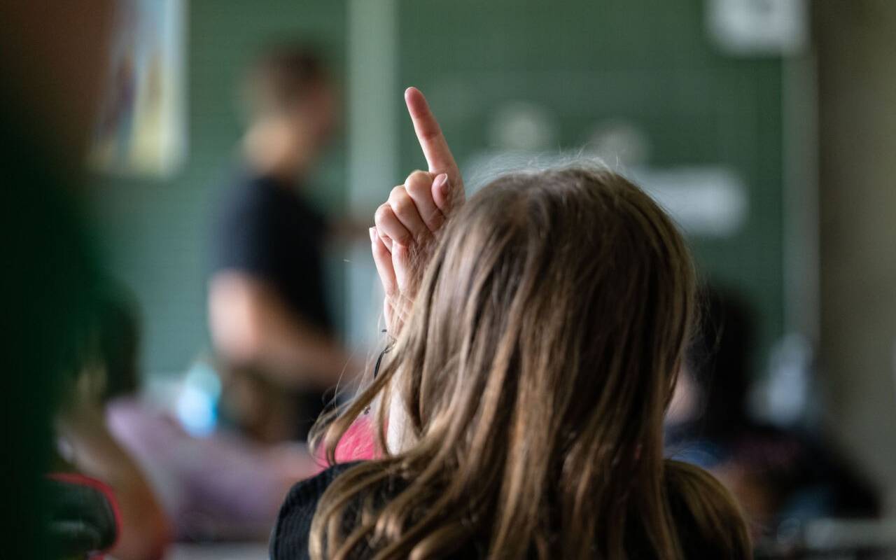 Schülerinnen und Schüler einer vierten Klasse einer Grundschule nehmen am Unterricht teil, eine Schülerin meldet sich.