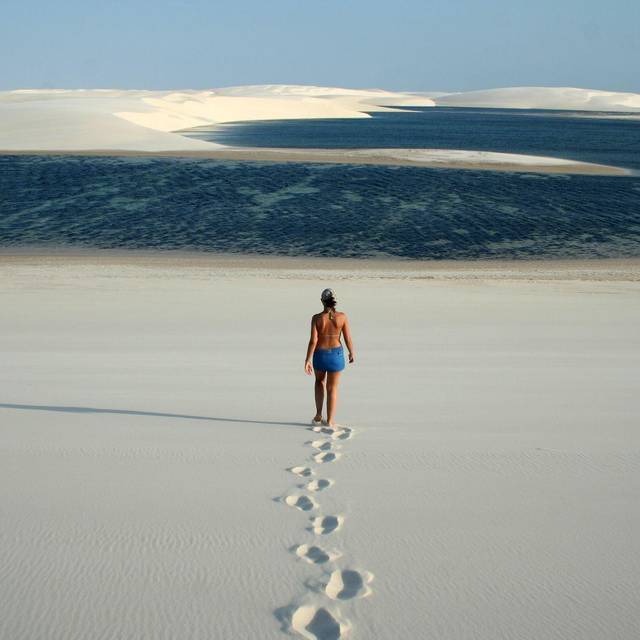 Frau läuft durch Dünenlandschaft zu einer kleinen Lagune