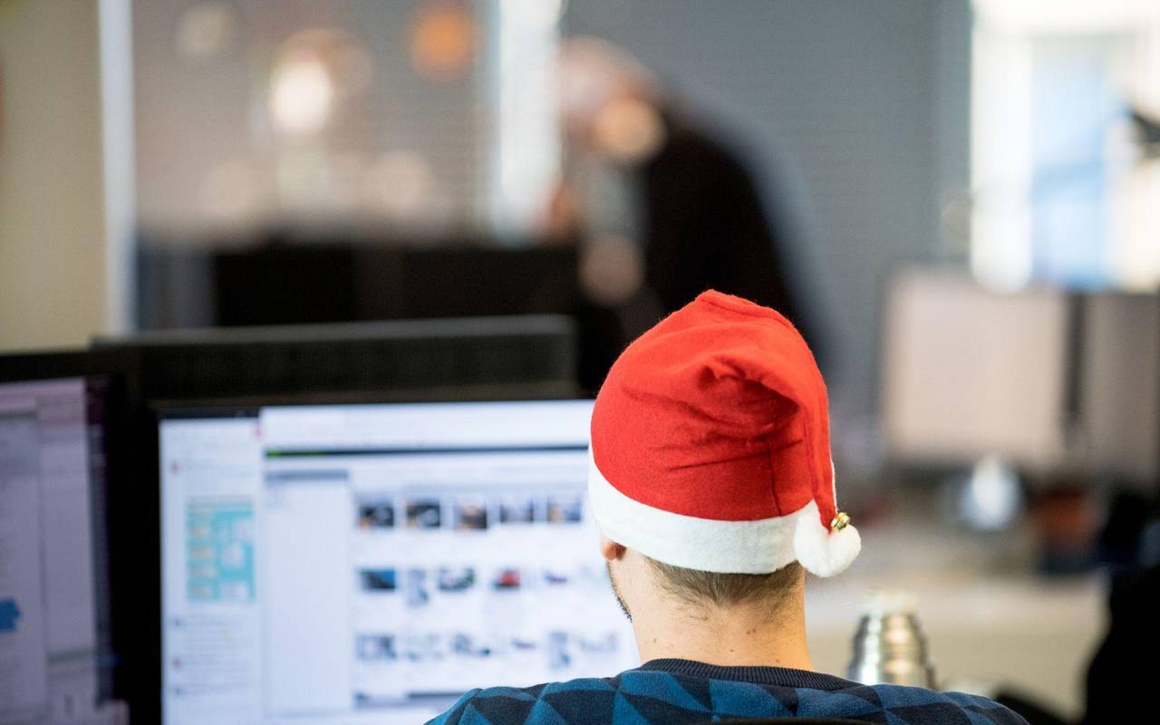 Ein Mann sitzt mit Weihnachtsmütze im Büro