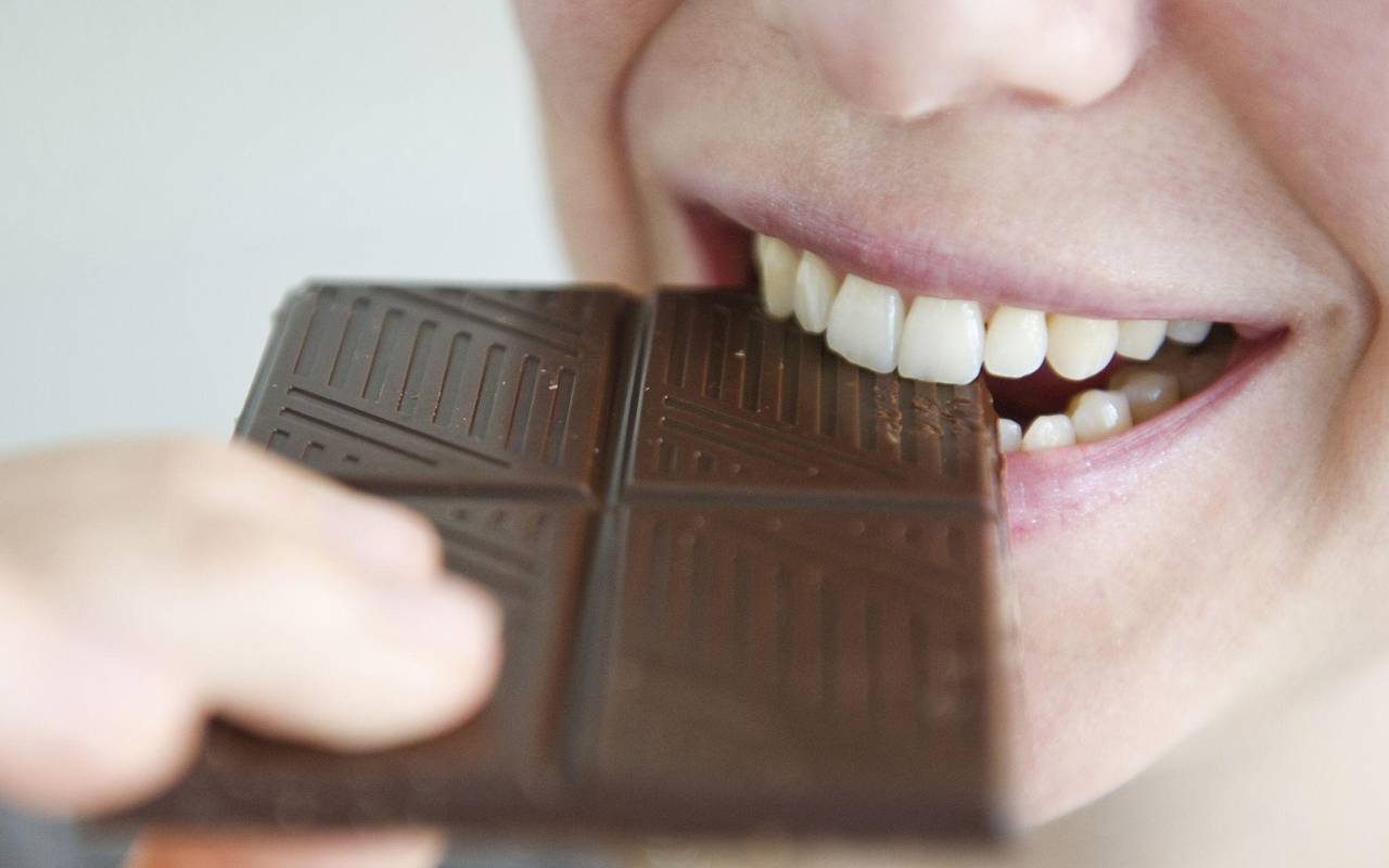 Frau beißt in ein Stück Schokolade