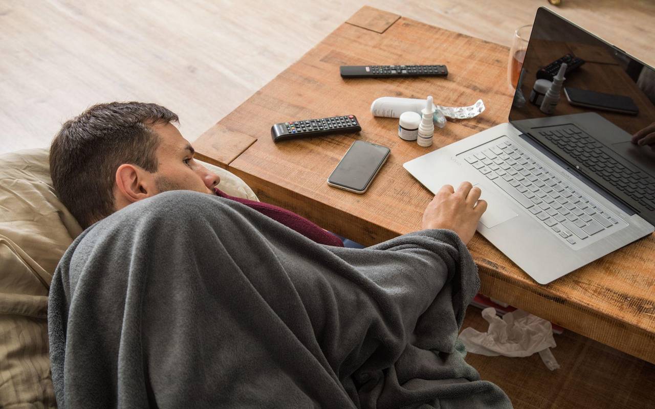 Ein Mann mit Erkltung bedient ein Laptop