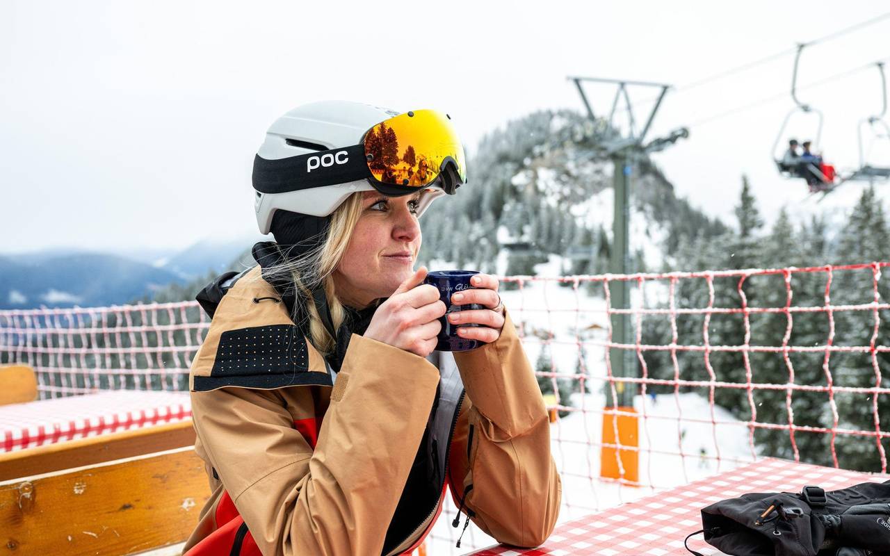Eine Wintersportlerin wärmt sich mit einem Heißgetränk auf
