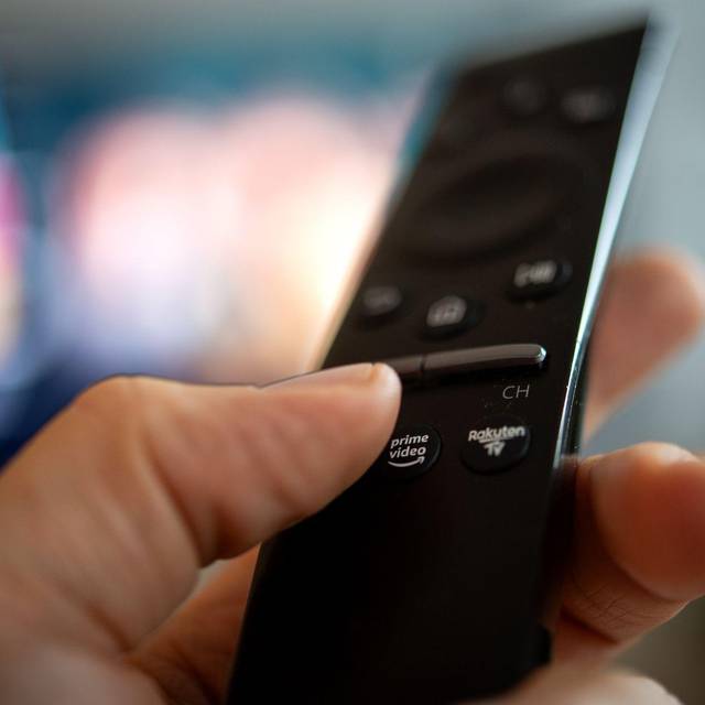 Ein Mann hält eine Fernbedienung mit der Aufschrift Amazon Prime