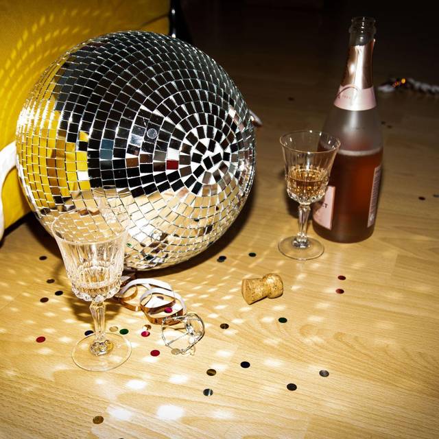 Discokugel liegt neben Sektflaschen und Gläsern auf dem Boden