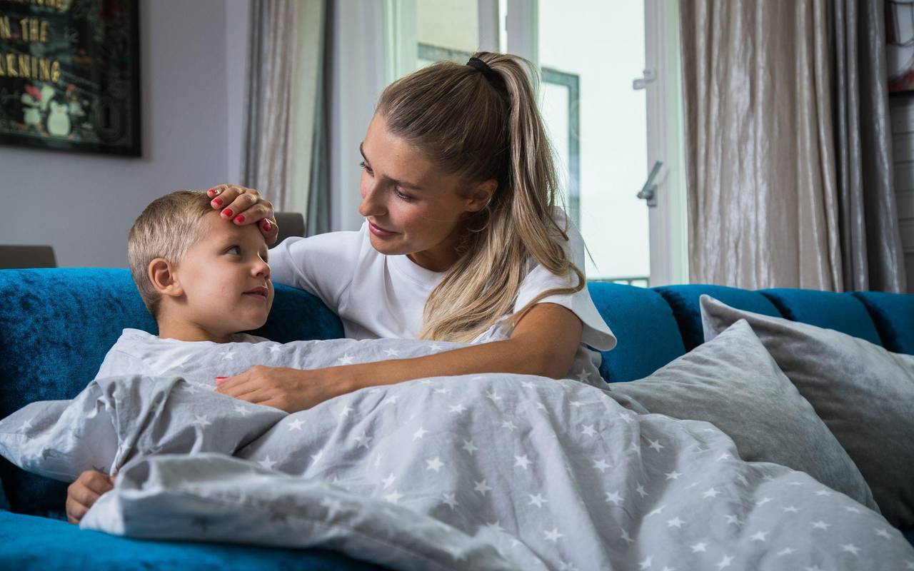 Eine Mutter kümmert sich um ihr kranken Kind mit Fieber