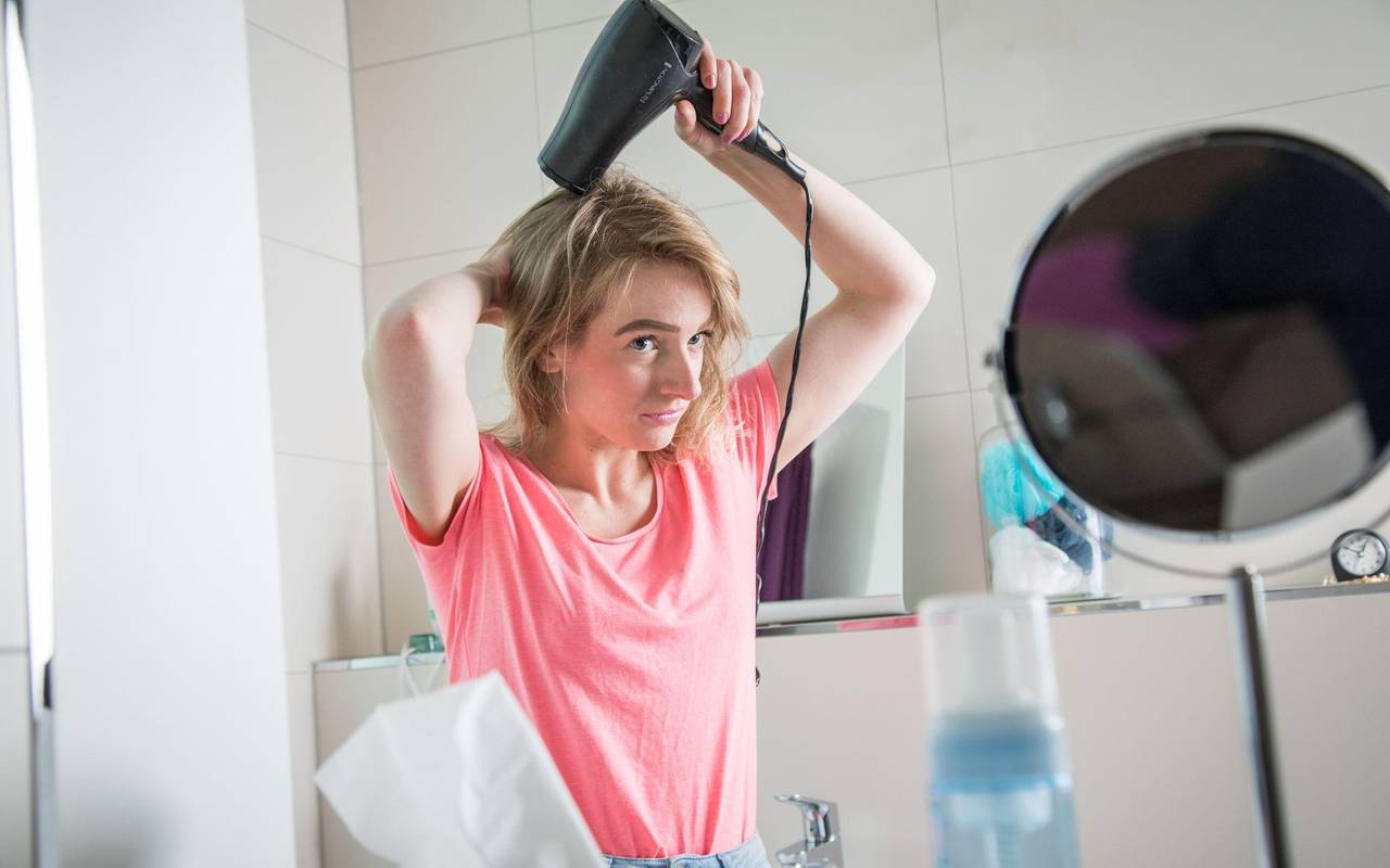 Eine junge Frau föhnt ihre Haare