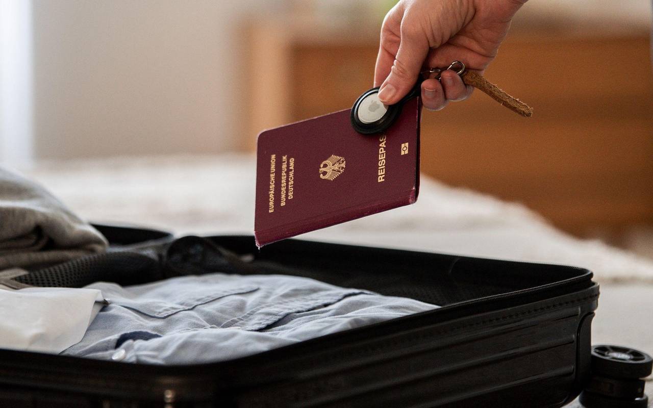 Eine Frau legt Airtag und Reisepass in einen Koffer