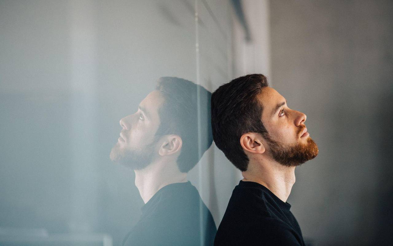 Ein junger Mann lehnt nachdenklich an einer Glaswand