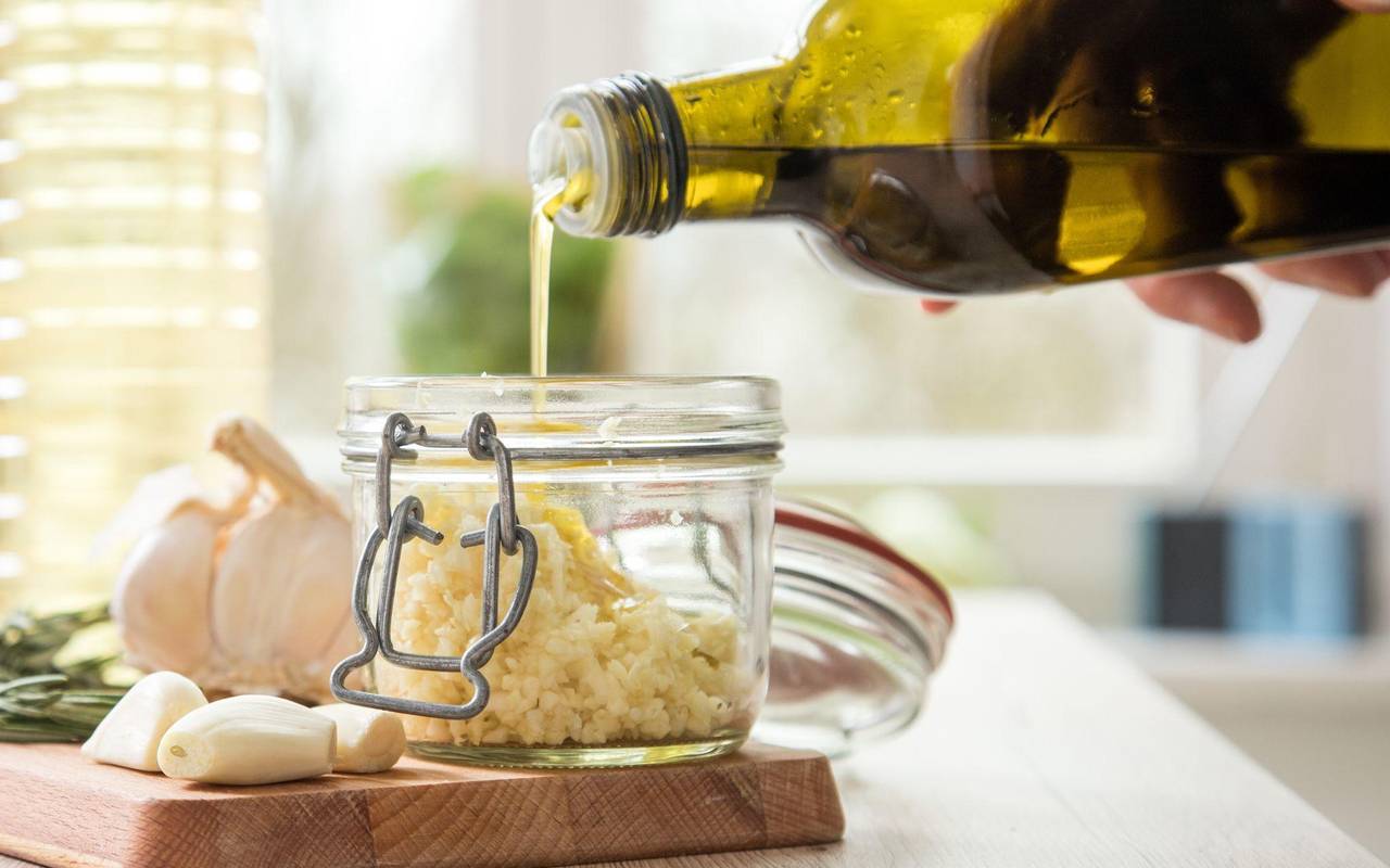 Olivenöl wird in ein Einmachglas geschüttet
