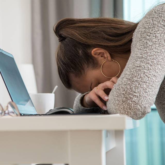 Eine junge Frau legt den Kopf auf den Tisch