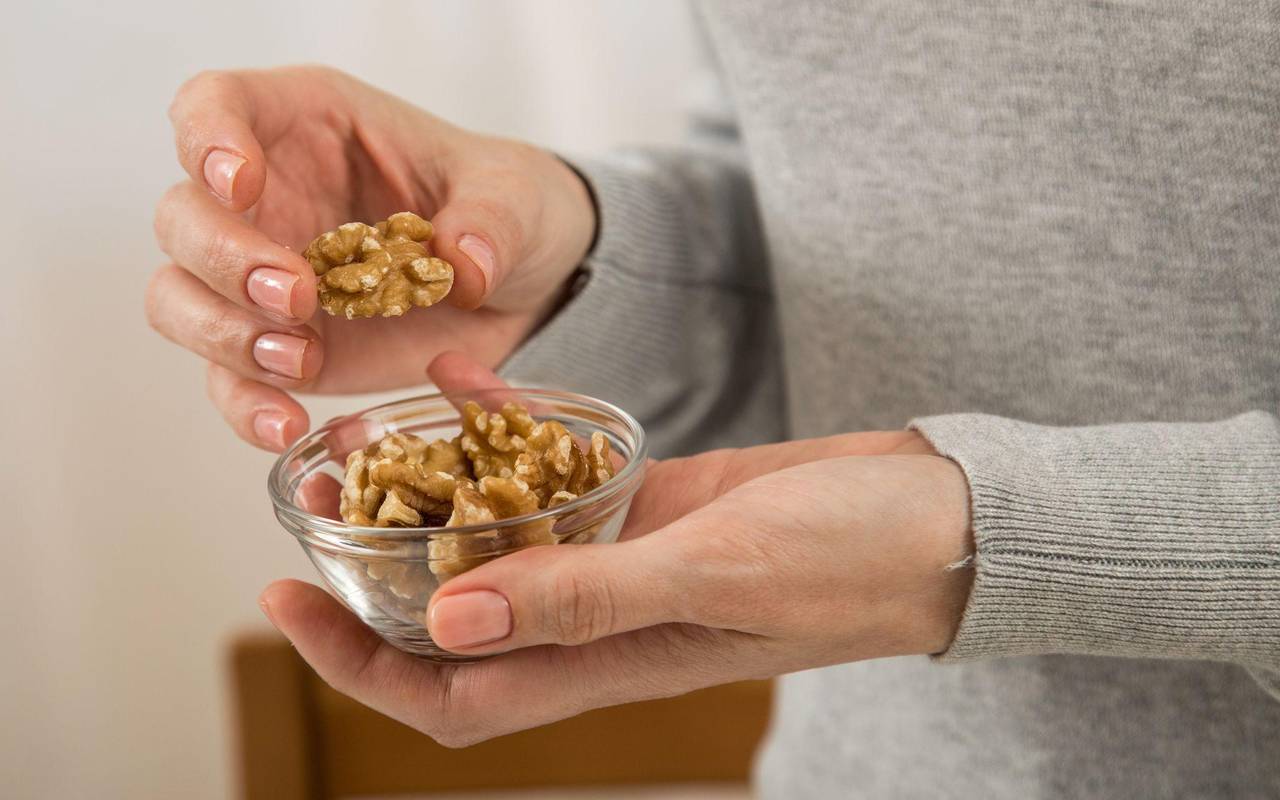 Eine Frau hält ein Schälchen mit Walnüssen in der Hand