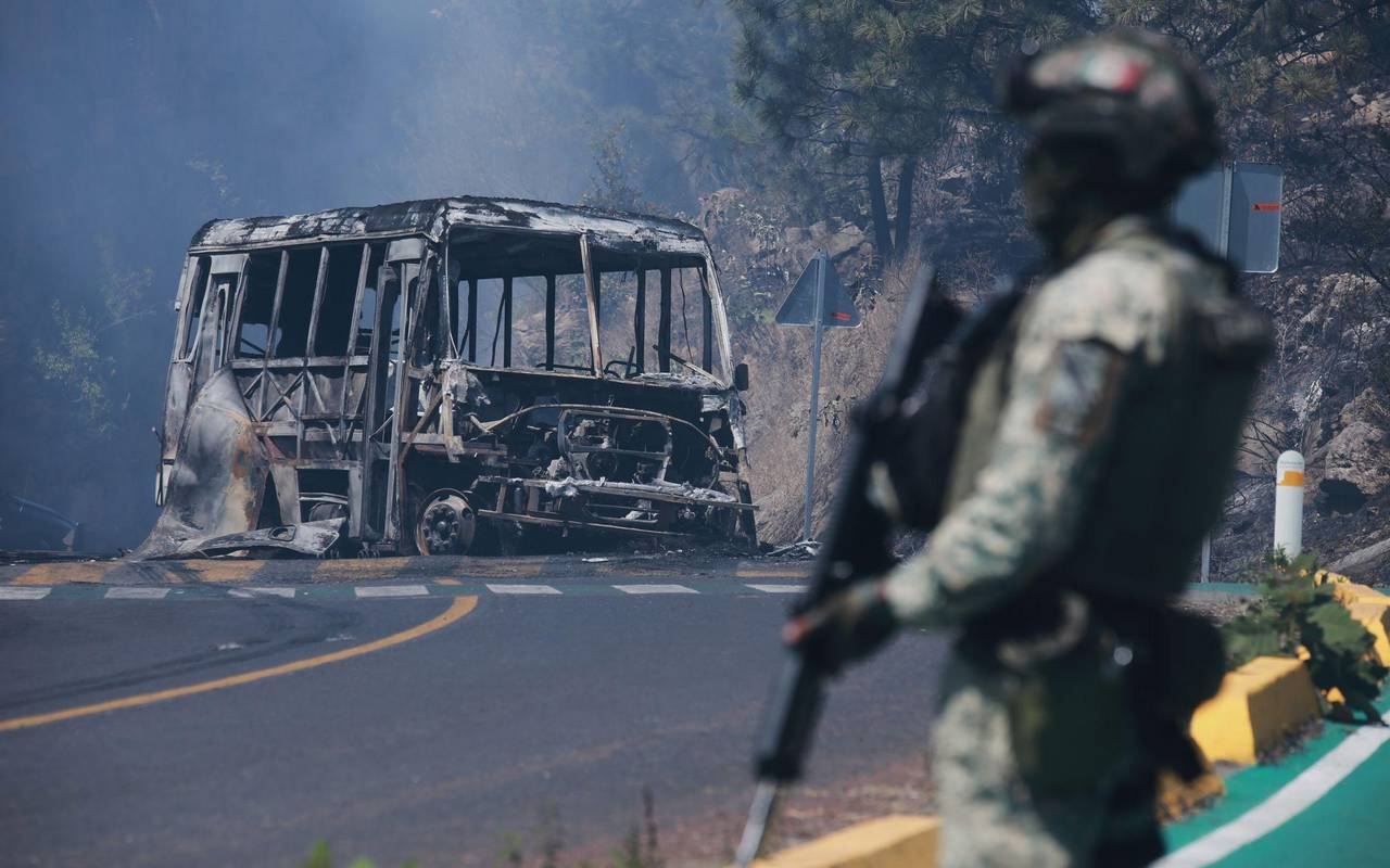 Ein Soldat steht in Cointzio neben einem ausgebrannten Bus