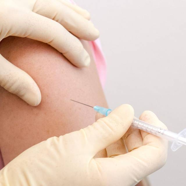 Eine Frau wird in den Oberarm geimpft