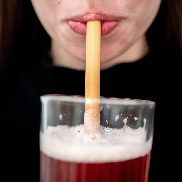 Eine junge Frau trinkt durch einen Trinkhalm aus Bambus