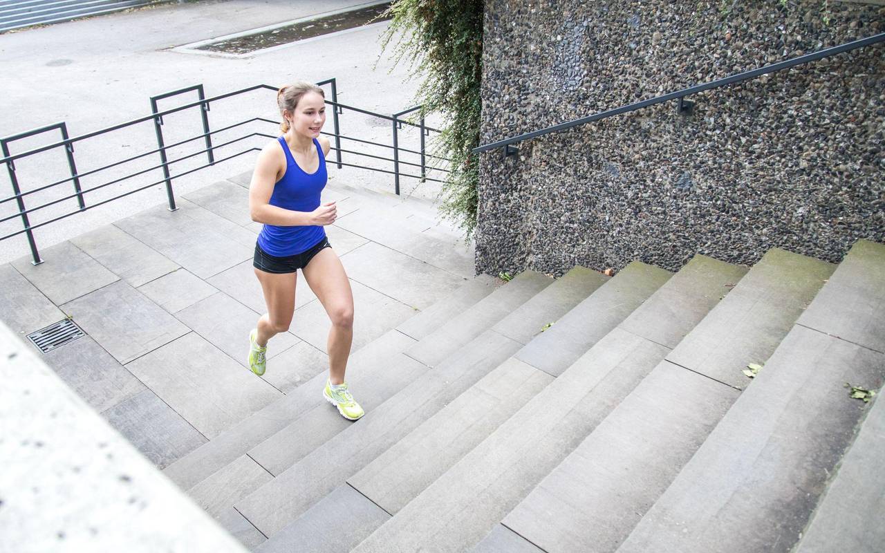 Frau joggt im Park die Stufen einer Treppe empor