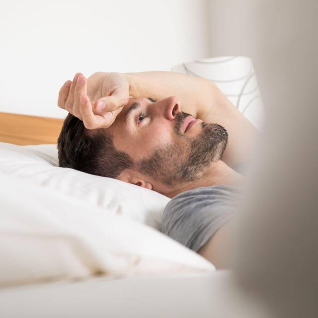 Ein junger Mann liegt im Bett
