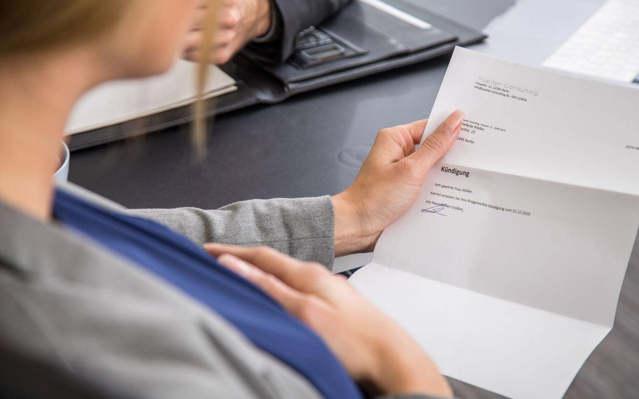 Eine schwangere Frau hält eine Kündigung in der Hand