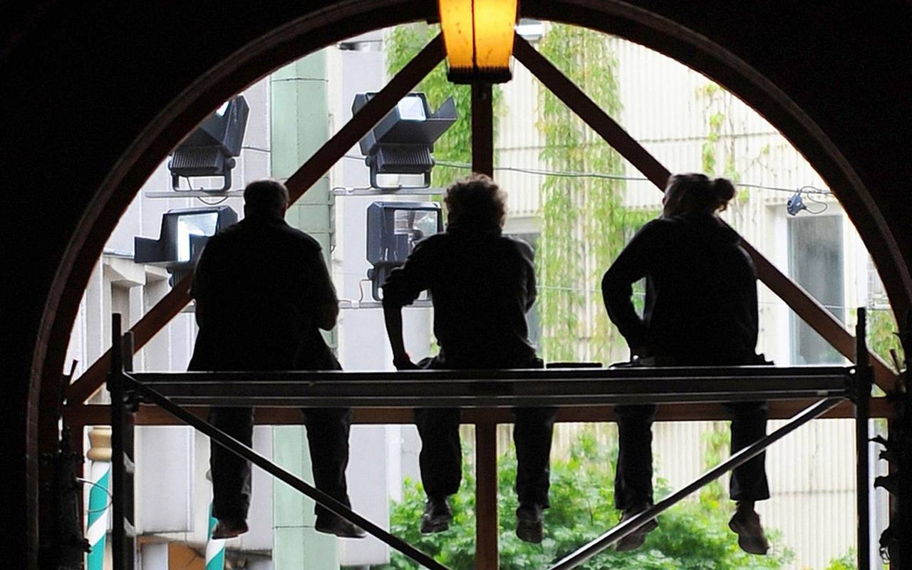 Arbeiter sitzen auf einem Baugerüst