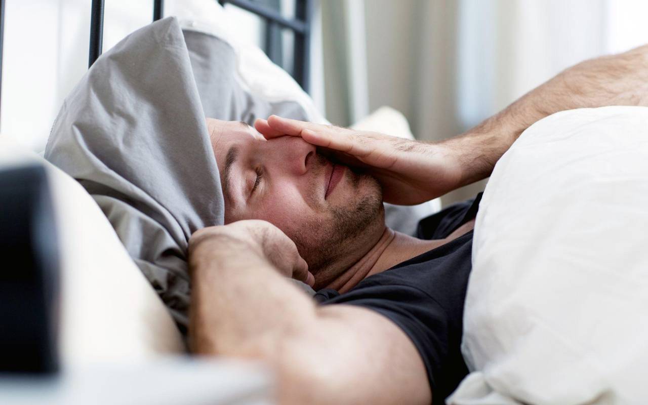 Ein Mann liegt verschlafen im Bett