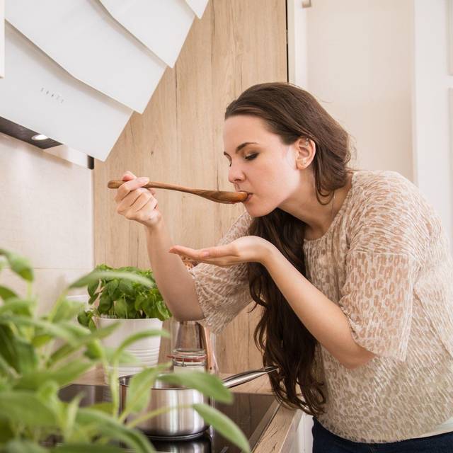 Eine Frau kostet eine Suppe, Käuter im Vordergrund