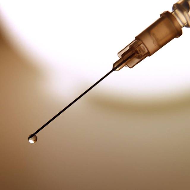 Eine Flüssigkeit tropft aus der Kanüle einer Spritze