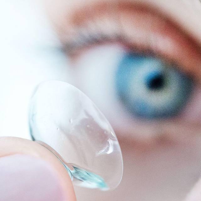 Eine Person hält eine Kontaktlinse auf dem Finger