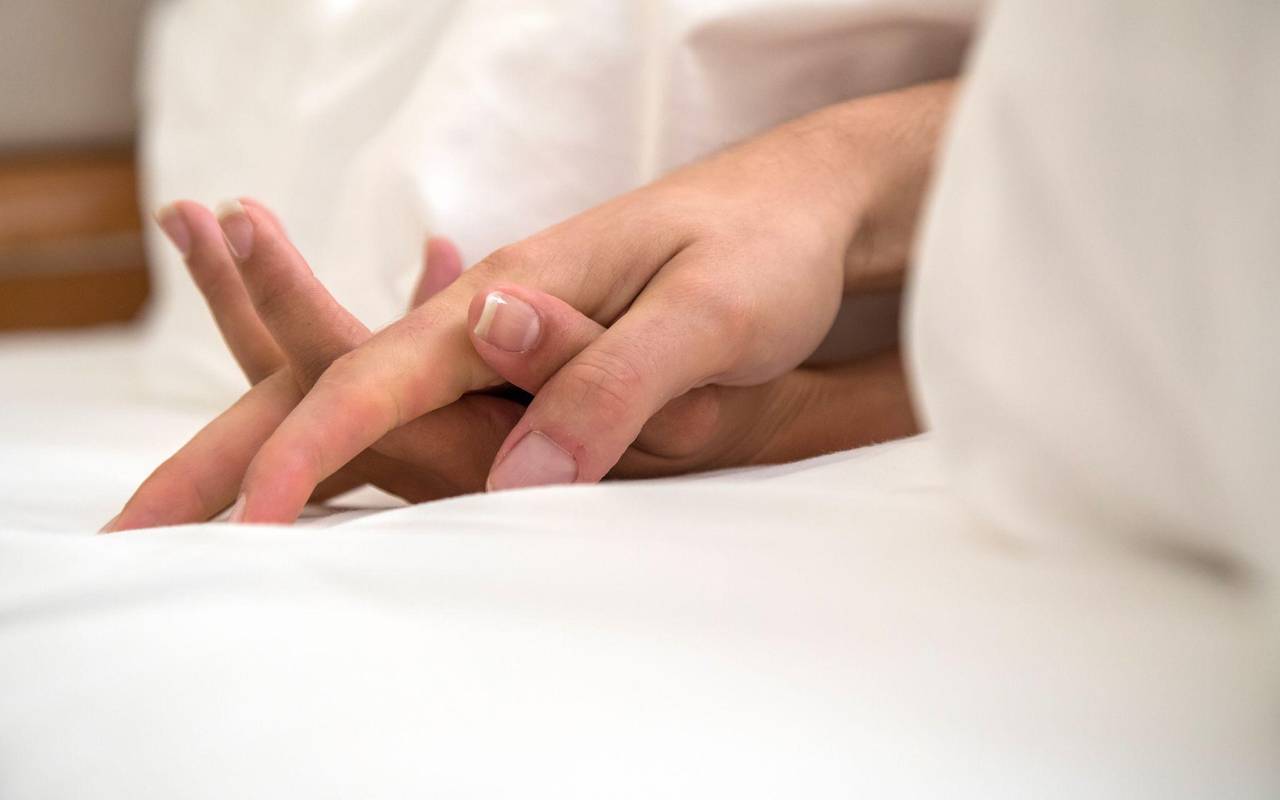 Zwei ineinander liegende Hände sind unter einer Decke zu sehen