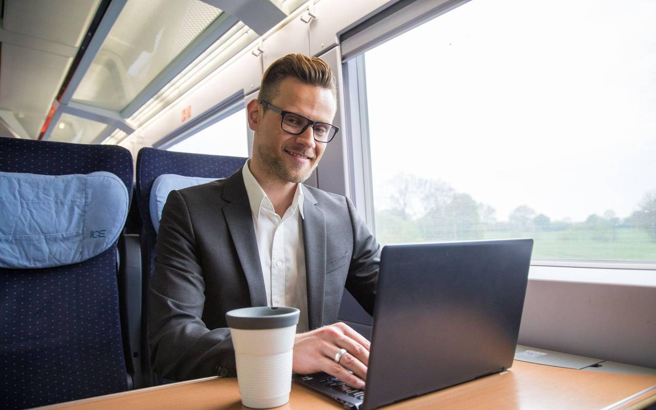 Ein mann arbeitet in einem Zug an einem Laptop