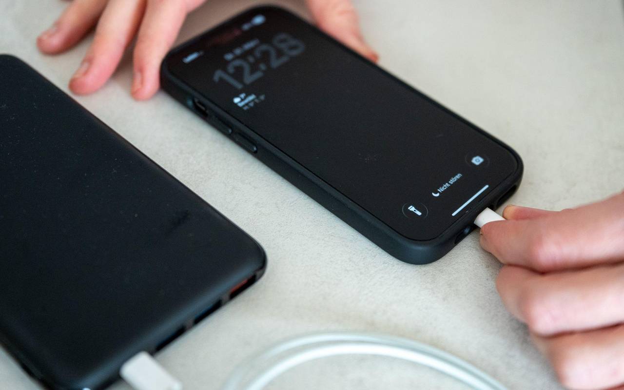 Eine Frau schließt ein iPhone an eine Powerbank an