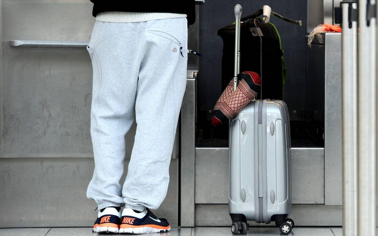 Ein Passagier in Jogginghose steht bei der Gepäckabgabe