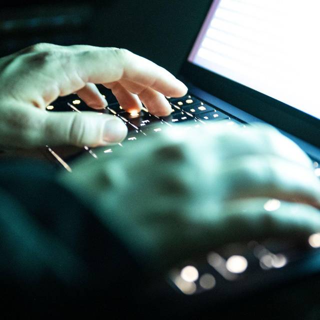 Eine Person tippt auf einer beleuchteten Laptop-Tastatur