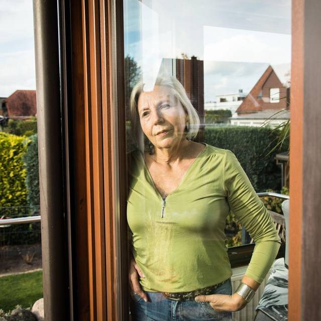 Eine Frau blickt aus einem Fenster auf einen Garten
