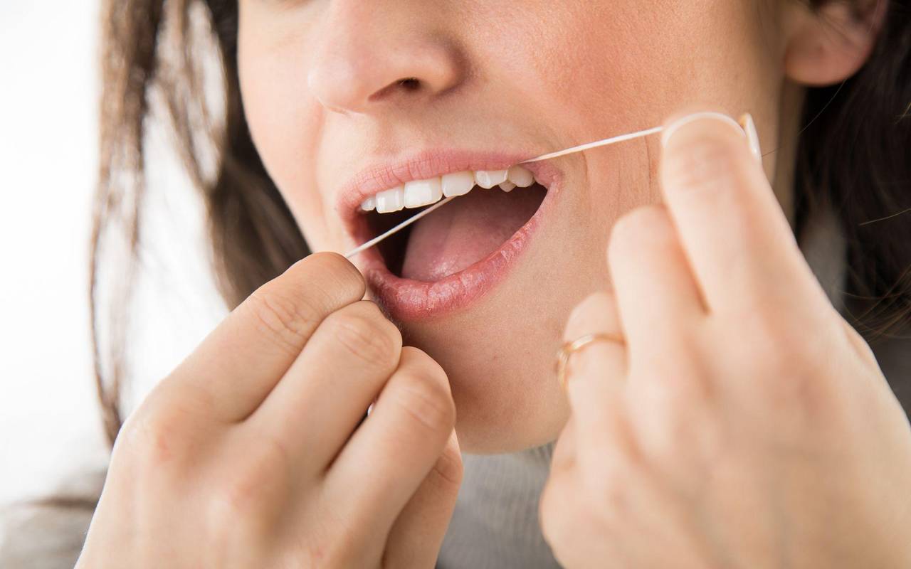 Eine Frau benutzt Zahnseide
