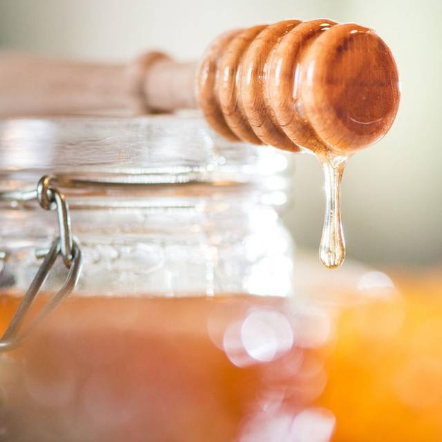 Honig tropft von einem Honiglöffel aus Holz