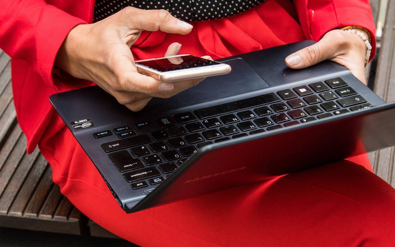 Eine Frau hält ein Smartphone und ein Laptop in den Händen