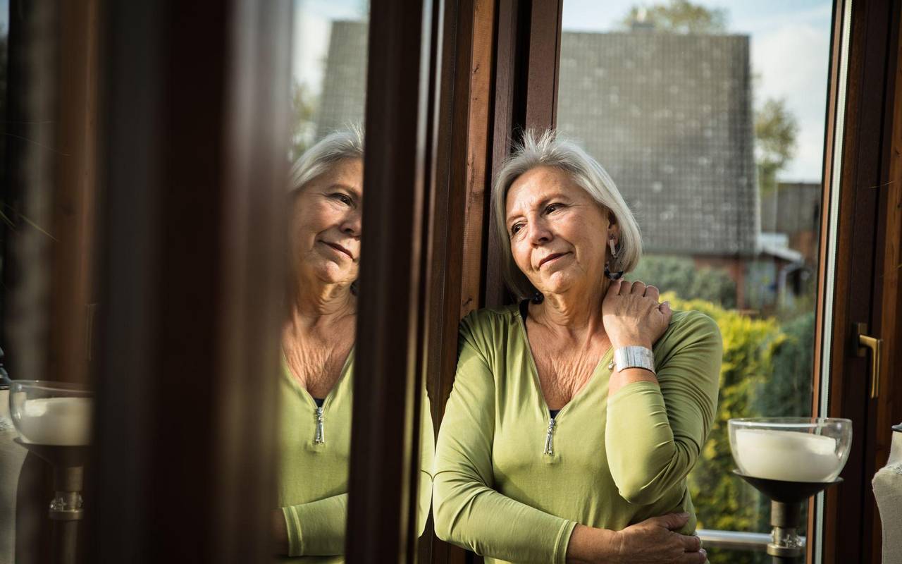 Eine ältere Frau schaut gedankenverloren aus dem Fenster