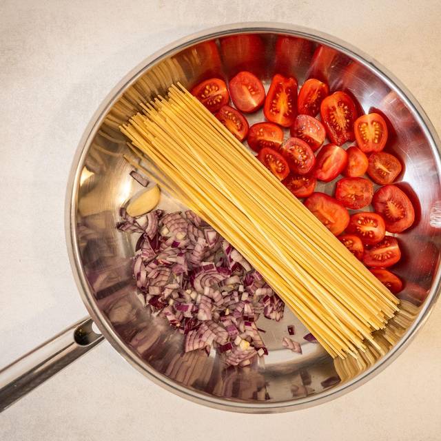 Spaghetti, Tomaten und Zwiebeln in einer Pfanne