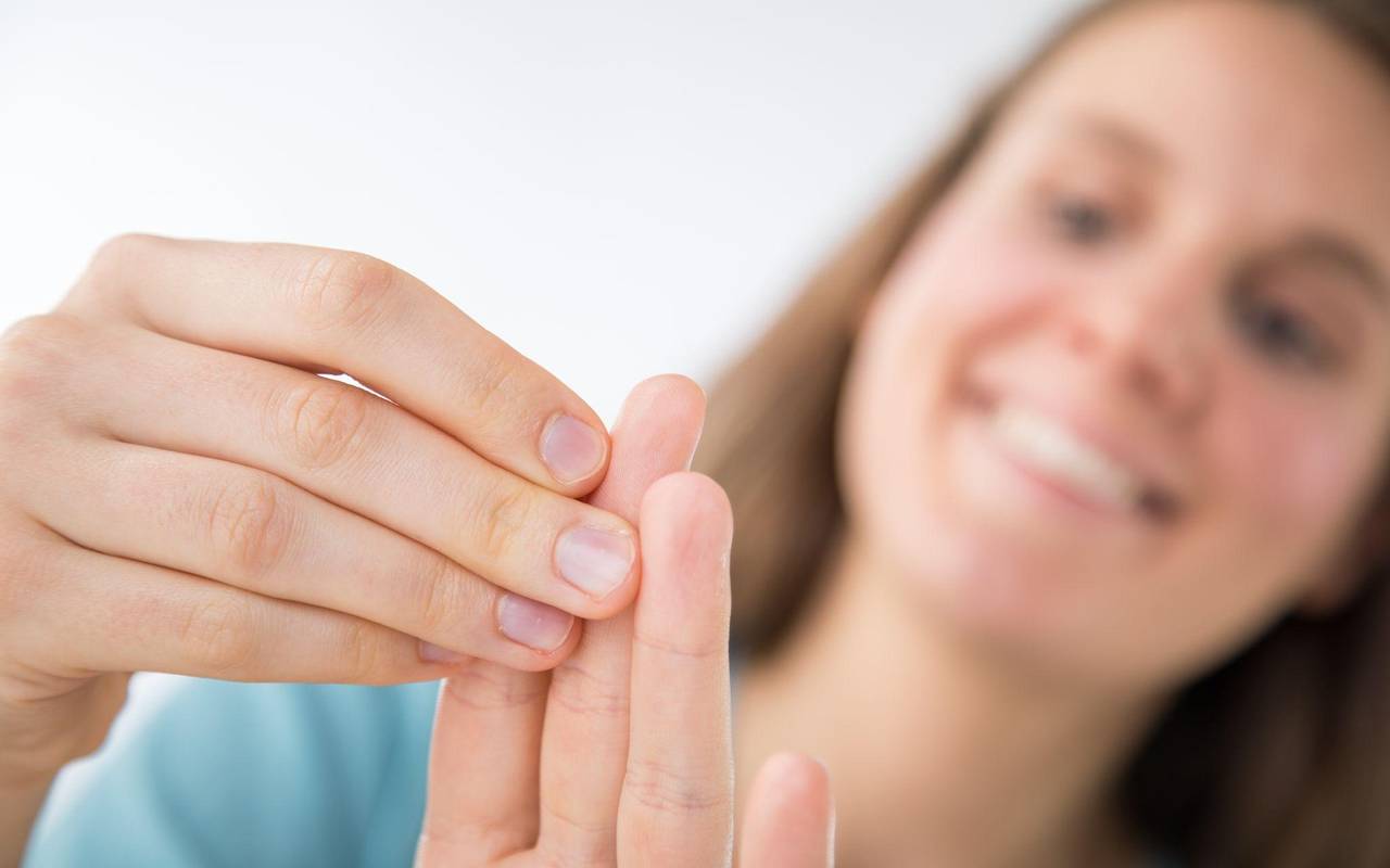 Eine Frau betrachtet ihre Fingernägel