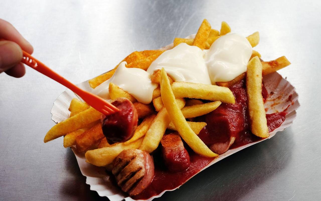 Eine Currywurst mit Pommes und Mayo