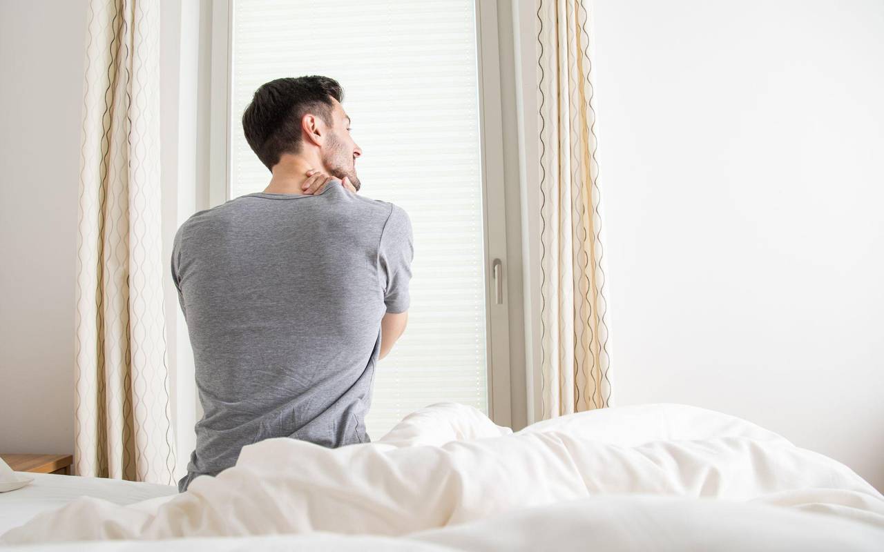 Ein Mann hält sich seine verspannten Muskeln am Nacken