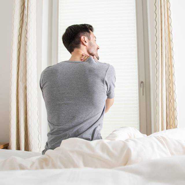 Ein Mann hält sich seine verspannten Muskeln am Nacken