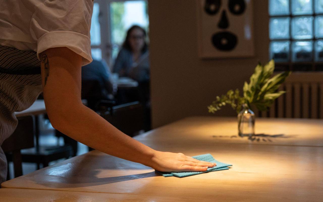 Eine Bedienung wischt einen Tisch im Restaurant sauber