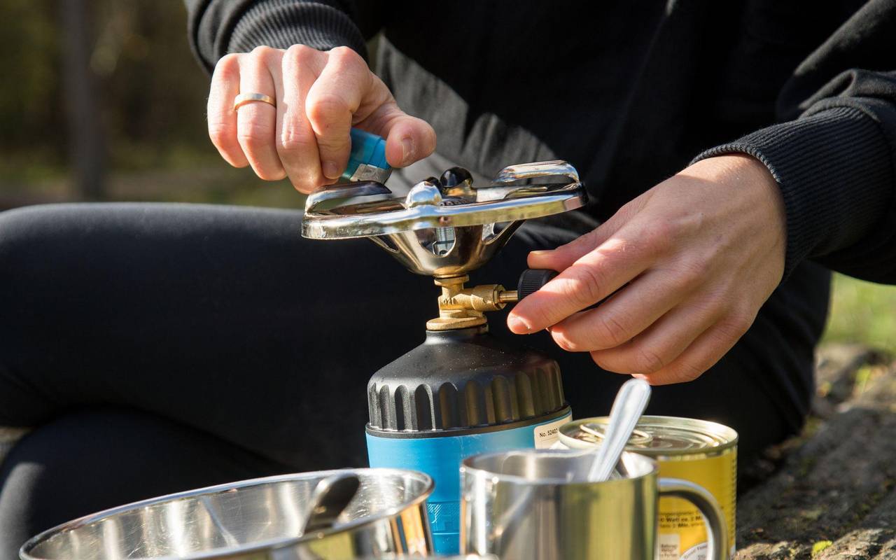 Frau bereitet Essen auf einem Campingkocher zu