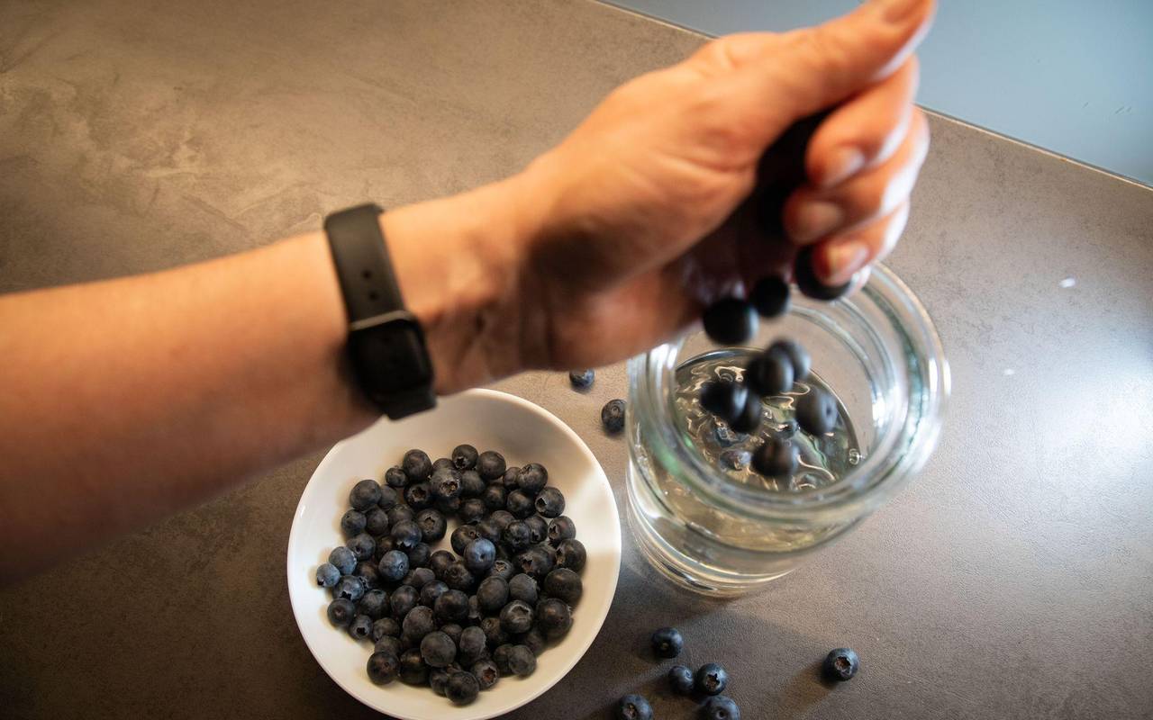 Frau gibt Blaubeeren in ein Glas mit Wasser