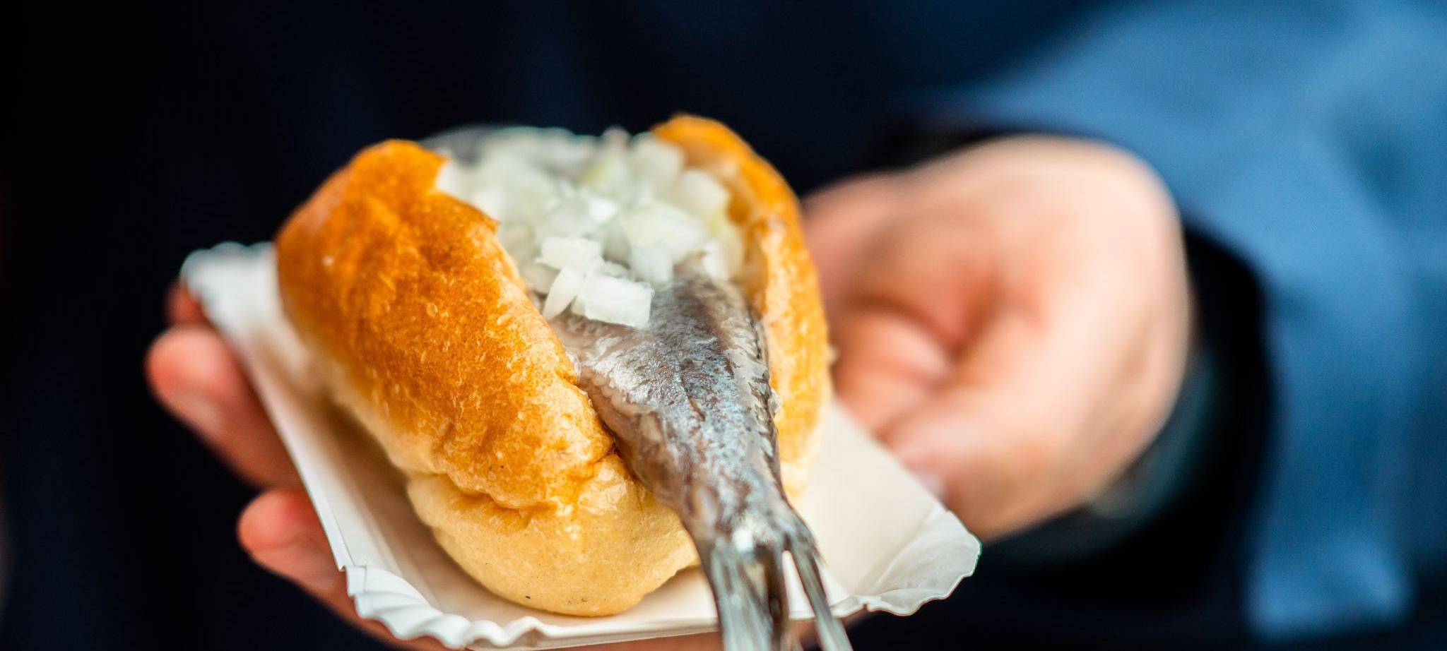 Person hält ein Matjesbrötchen in der Hand