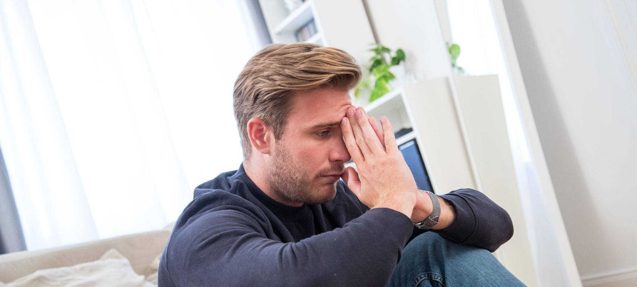 Ein junger Mann gestresst in einem Wohnzimmer
