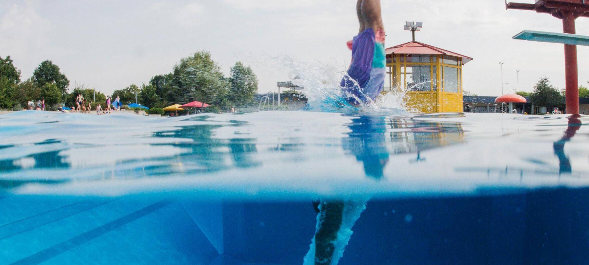 Schwimmer springt vom Sprungturm ins Wasser