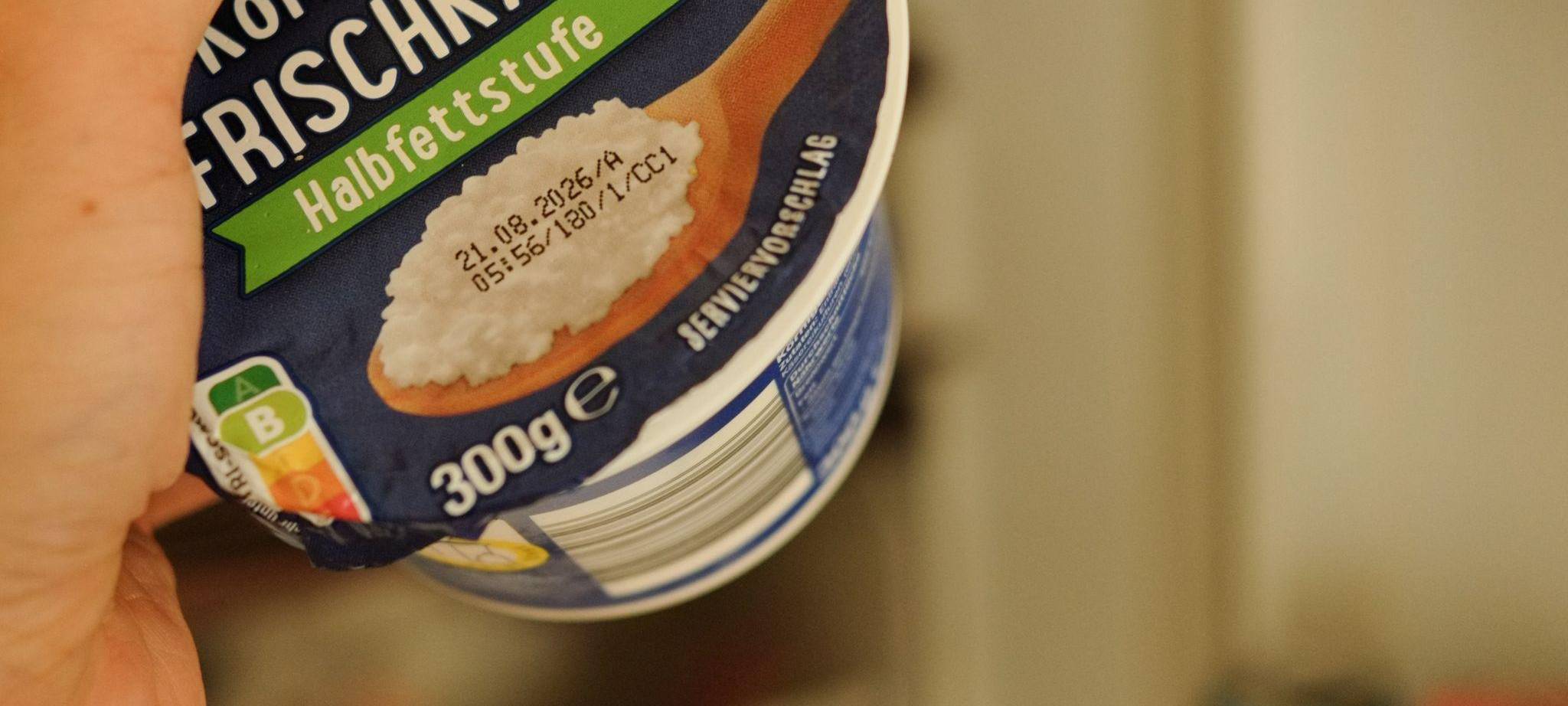 Ein Mann hält einen Becher körnigen Frischkäse in der Hand
